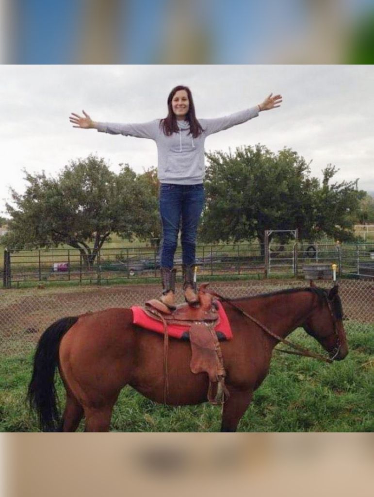 Standing up on a horse in the pasture.