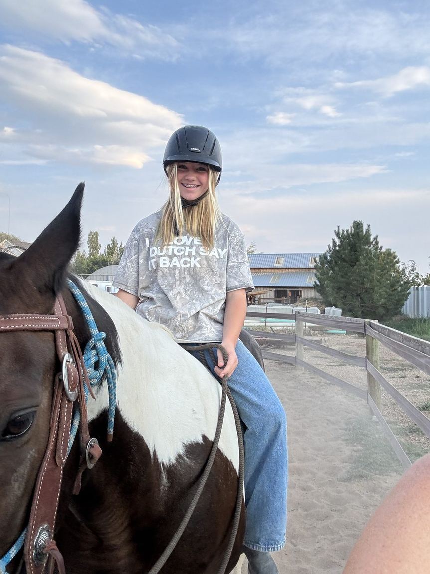 A young rider up on a paint horse.